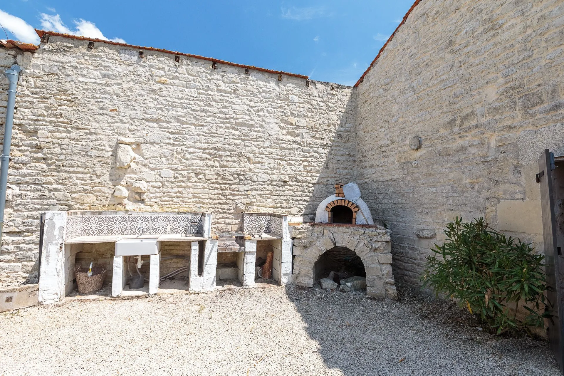 Cuisine d'été équipée avec barbecue et grande table pour repas conviviaux en extérieur